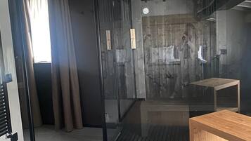 A modern room with a sliding glass door leading to a shower area, a wooden bench, and a tiled floor.