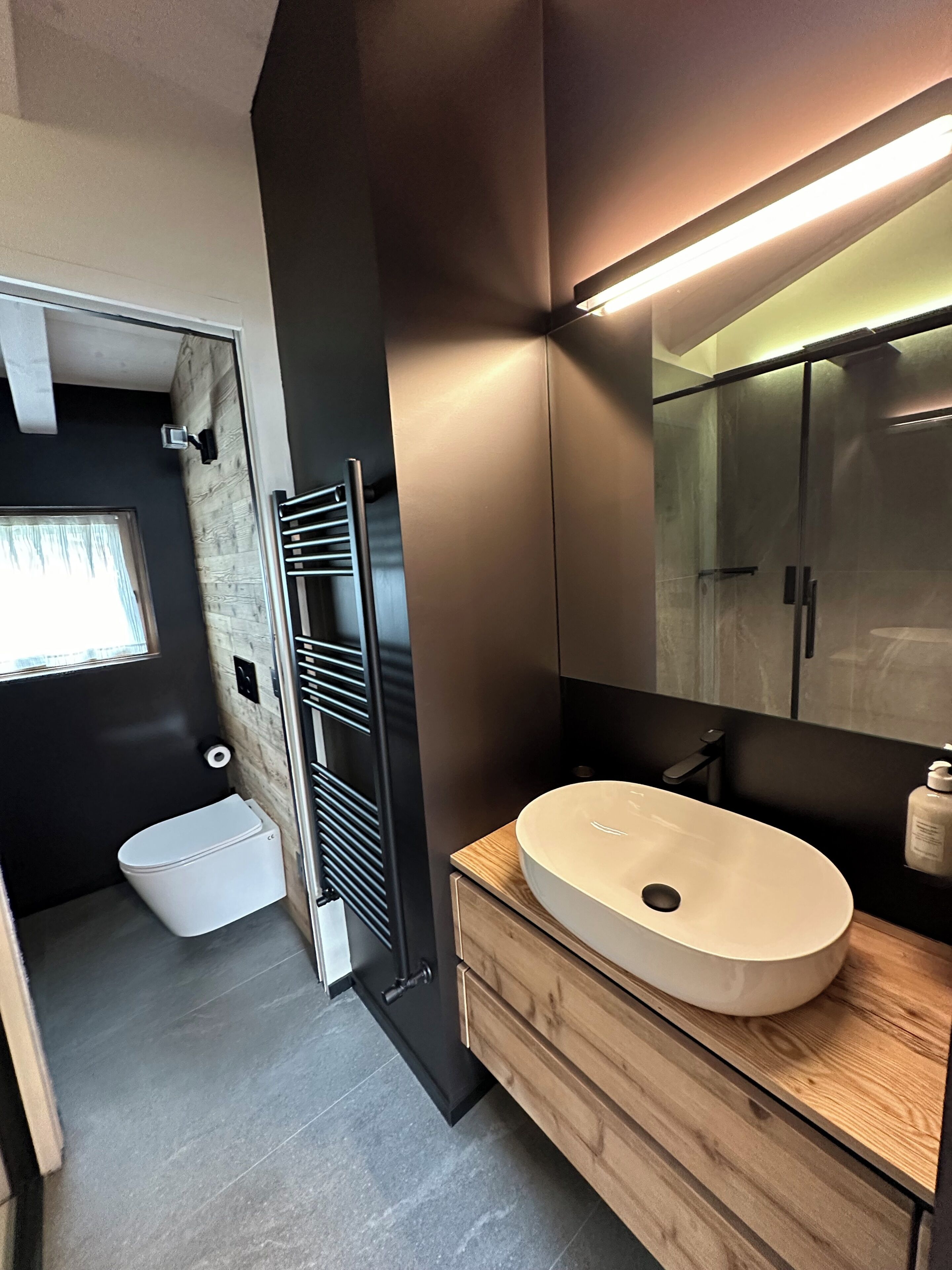 Un baño moderno con tocador de madera, un espejo grande y cabina de ducha de vidrio.