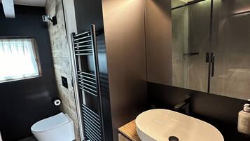Un baño moderno con tocador de madera, un espejo grande y cabina de ducha de vidrio.