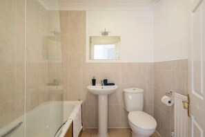 Un bagno con doccia vetrata, lavabo su piedistallo e water.