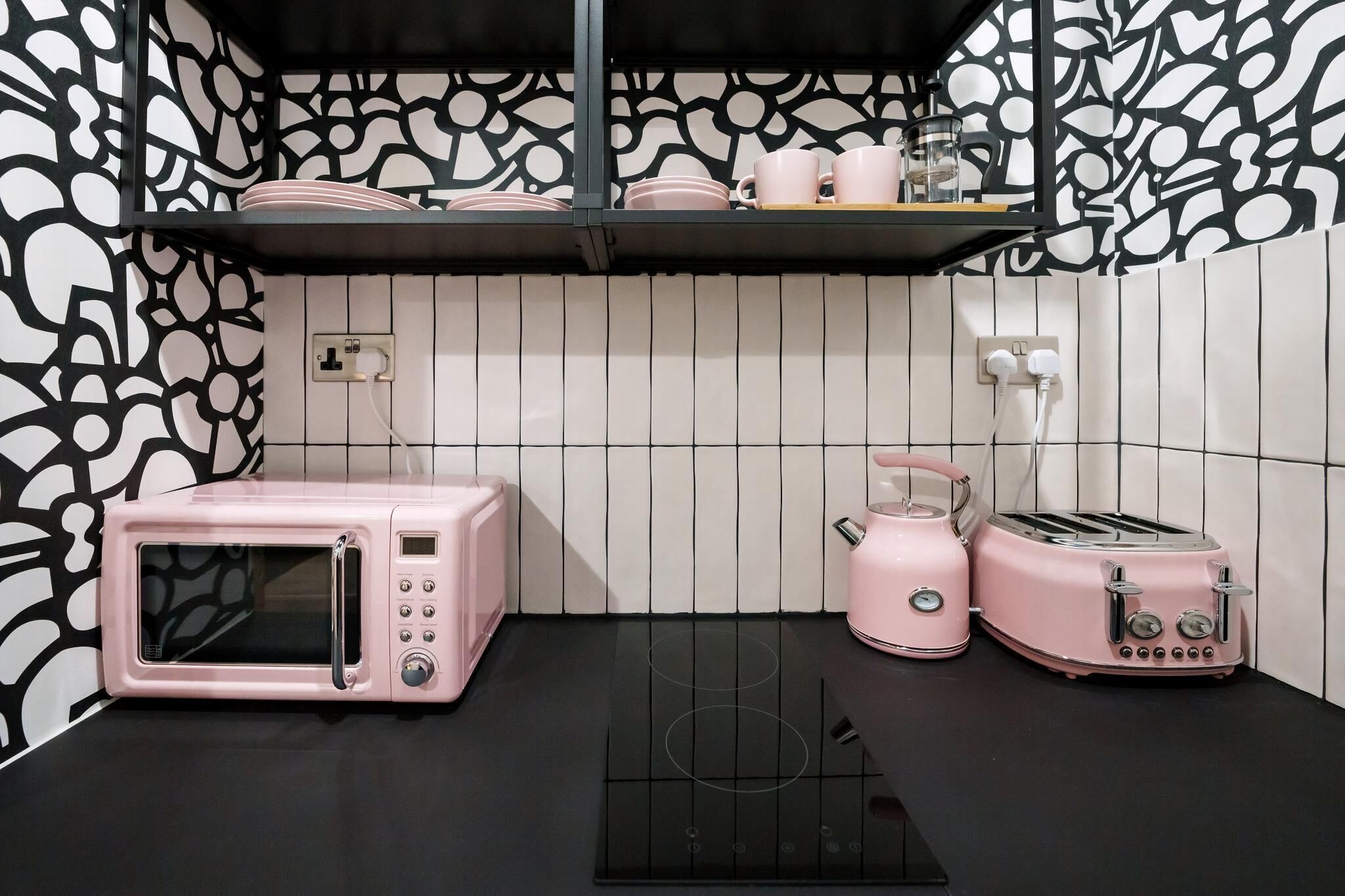 Eine Küchenzeile mit Mikrowelle, Toaster und Wasserkocher auf einer schwarzen Arbeitsplatte.