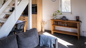 Um interior moderno com escada, sofá, mesa consola de madeira e janela com persianas.