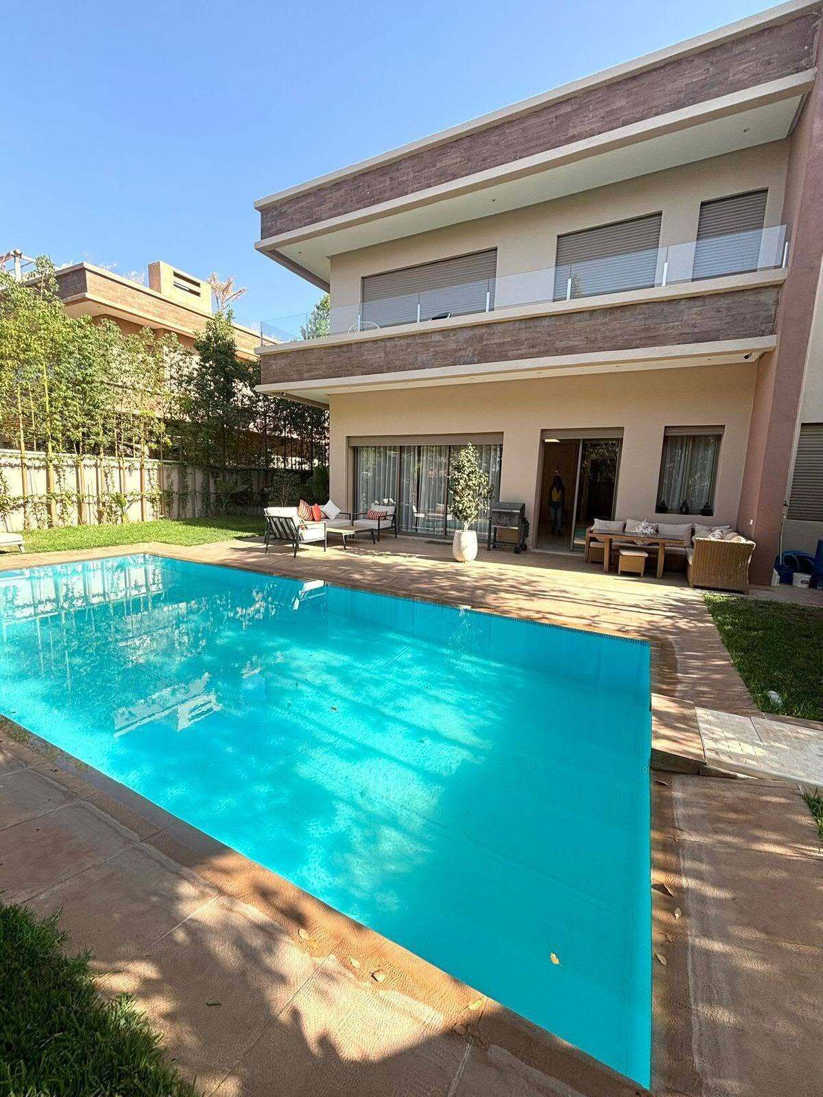 A modern two-story house with a swimming pool, outdoor furniture, and a covered patio area.