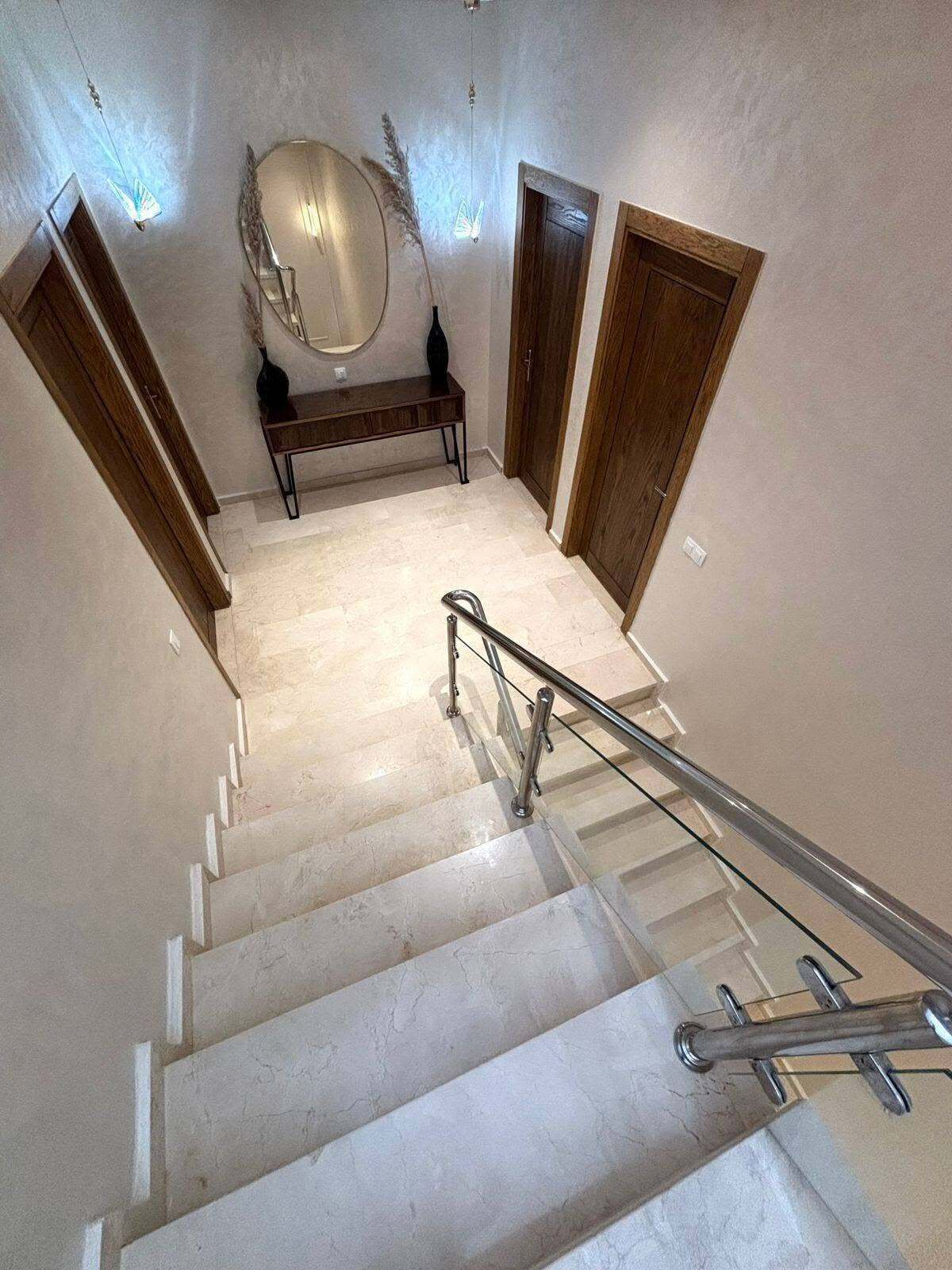A staircase with a glass railing, wooden doors, and a bench.