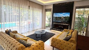 Moderni olohuone, jossa on suuri sohva, sohvapöytä ja televisio.