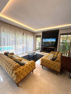 Ein modernes Wohnzimmer mit einer großen Couch, einem Couchtisch und einem Fernseher.