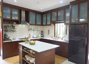 Een moderne keuken met houten kastjes, een centraal eiland en een zwarte koelkast.