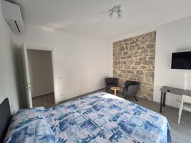 Habitación de hotel con cama, escritorio, dos sillas, un revestimiento de piedra y televisión.