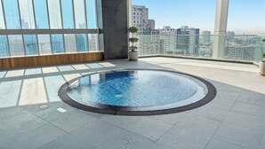 Una piscina sul tetto con vista sulla città, ampie finestre e piante in vaso.