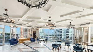 Un'ampia sala da conversazione con soffitto alto, grandi finestre e arredamento moderno.