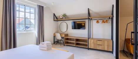 Ein modernes Hotelzimmer mit Bett, Schreibtisch, Fernseher und Stauraum.