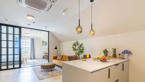 A modern kitchen with a central island, pendant lighting, and a view into the living area. - Stylish Coral Blue Condo at Bhome Punda Residences (Willemstad)