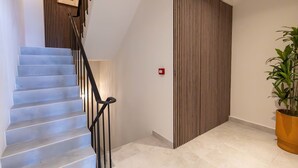 A staircase with a black railing, a wooden panel wall, and a potted plant. - Stylish Coral Blue Condo at Bhome Punda Residences (Willemstad)