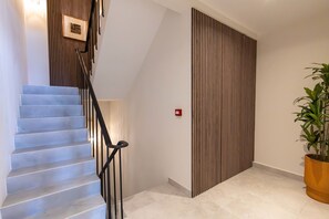 A staircase with a black railing, a wooden panel wall, and a potted plant. - Stylish Coral Blue Condo at Bhome Punda Residences (Willemstad)