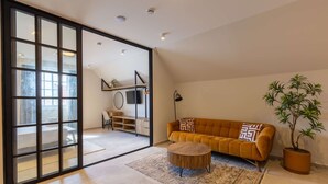 A modern living room with a sofa, a coffee table, a potted plant, and a sliding glass door leading to another room. - Stylish Coral Blue Condo at Bhome Punda Residences (Willemstad)