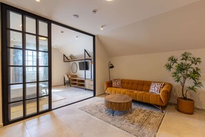 A modern living room with a sofa, a coffee table, a potted plant, and a sliding glass door leading to another room. - Stylish Coral Blue Condo at Bhome Punda Residences (Willemstad)