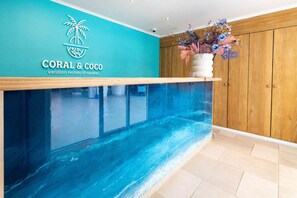 A reception area with a teal wall, a wooden reception desk, a large aquarium, and a wooden cabinet. - Chic, Urban, City Stays Bhome Punda Residences (Willemstad)