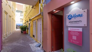 Un callejón estrecho con un edificio a la derecha que muestra un letrero de B-Home Apartments.