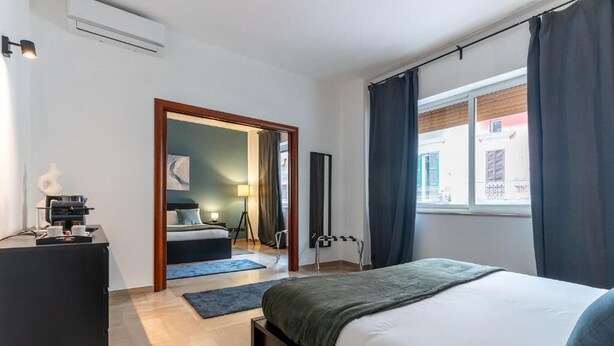 A modern hotel room with a bed, a desk, a lamp, and a view of the street. - Fourooms Bari - Principe Amedeo (Bari)