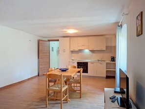 Ein kompakter Wohnbereich mit Essplatz, Küchenzeile und Fernseher.