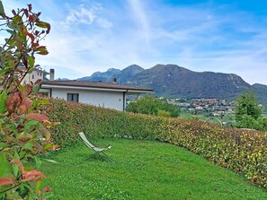 Ein Haus mit Garten, einer Liege und Blick auf eine Stadt und Berge im Hintergrund.