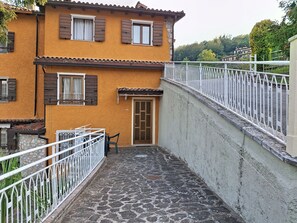 Ein Gebäude mit einem gepflasterten Innenhof, einem weißen Metallgeländer und einer Tür mit Fenster.
