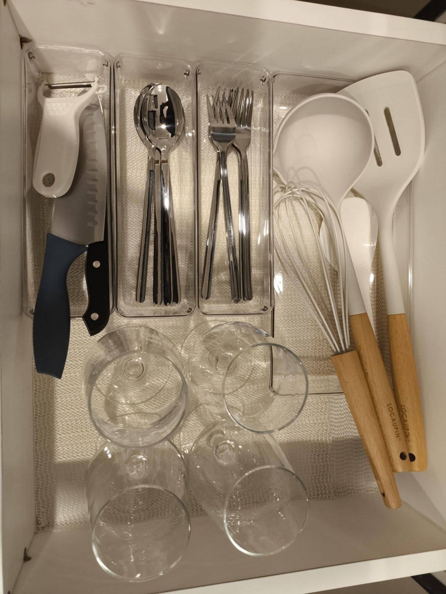 Eine Schublade mit Küchenutensilien, darunter ein Messer, Löffel, Gabeln und ein Schneebesen.