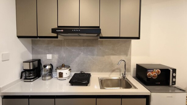 A kitchen with a stove, coffee maker, kettle, and a toaster. - Modern Studio at Megatower 7 Walk to SM, Session Rd and Burnham Park (Baguio)