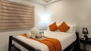 A hotel room with a bed, bedside table, lamp, and a window with blinds. - Modern Studio at Megatower 7 Walk to SM, Session Rd and Burnham Park (Baguio)