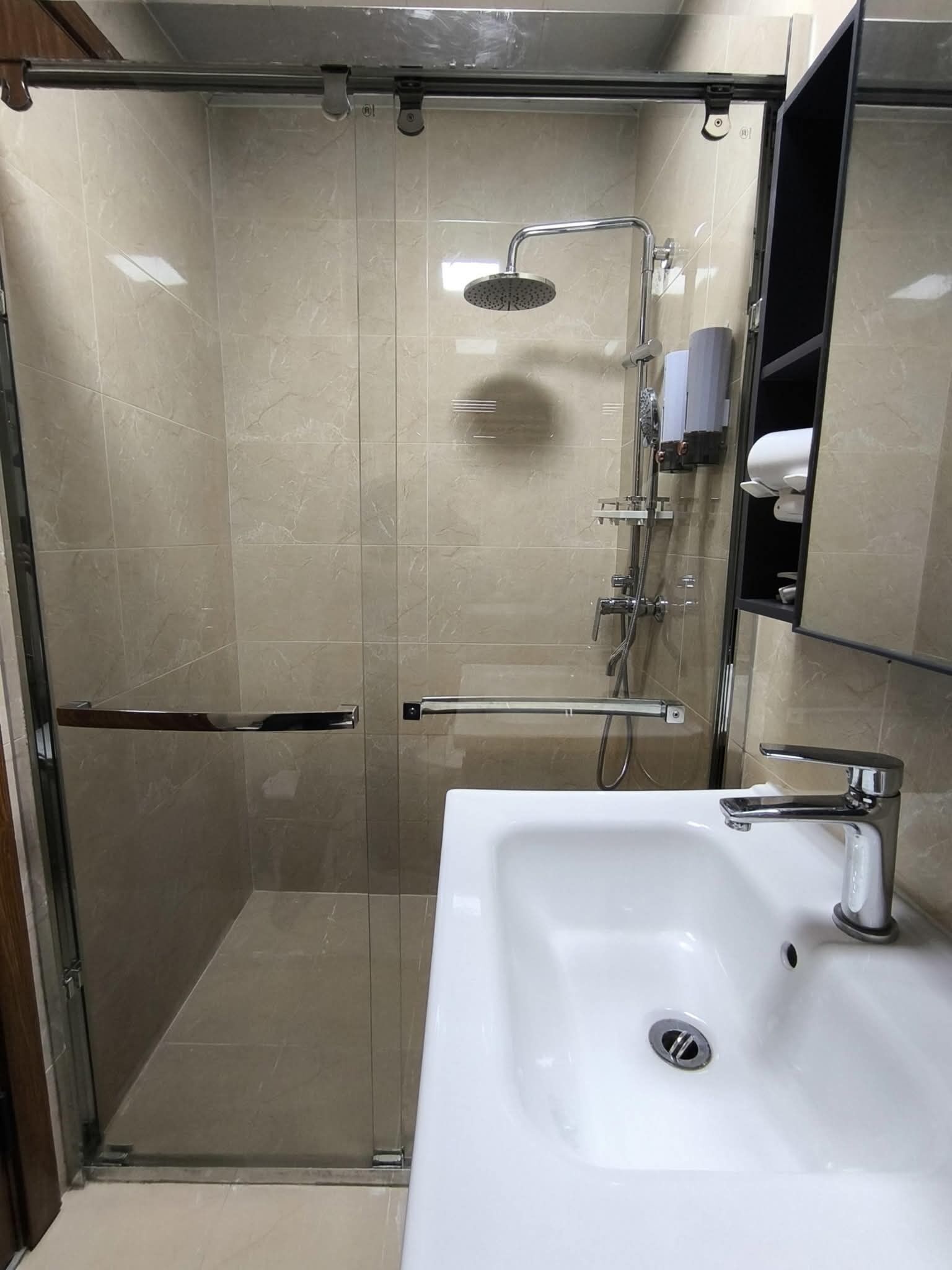 Ein modernes Badezimmer mit einer gläsernen Duschkabine, einem weißen Waschbecken und einem Spiegelkorpus.