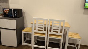 A kitchenette with a refrigerator, microwave, and wooden chairs. - Modern Studio at Megatower 7 Walk to SM, Session Rd and Burnham Park (Baguio)