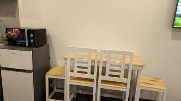 Eine Küchenzeile mit Kühlschrank, Mikrowelle und Holzkohle-Stühlen.