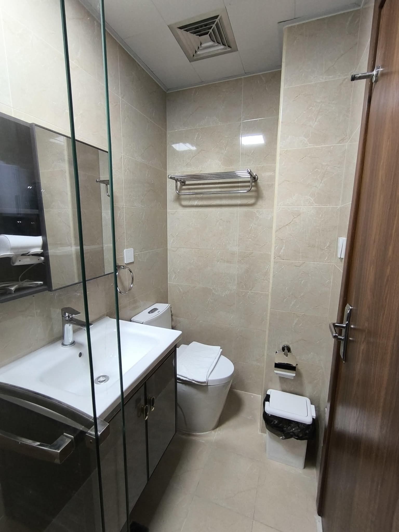 A modern bathroom with a glass partition, a sink, a toilet, and a shower area.