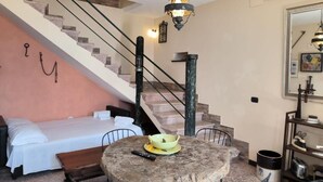 A bedroom with a bed, a round table with a bowl, a chair, a staircase, and a hanging light fixture. - Casal Trinacria - 1-Bedroom Apartment with Panoramic Jacuzzi (No. 5) (Sicilia)
