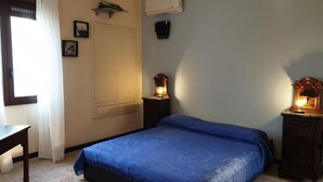 A bedroom with a bed, bedside tables, a desk, a window with curtains, and wall-mounted air conditioning units. - Casal Trinacria - 1-Bedroom Apartment with Panoramic Jacuzzi (No. 5) (Sicilia)