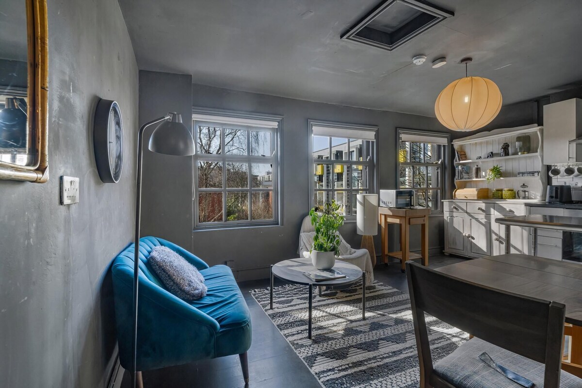 A modern kitchen with white cabinets, a dining table, and a blue sofa.