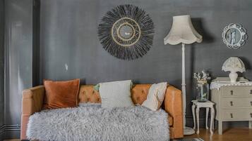 A room with a sofa, a lamp, a mirror, a vase, and a small table.