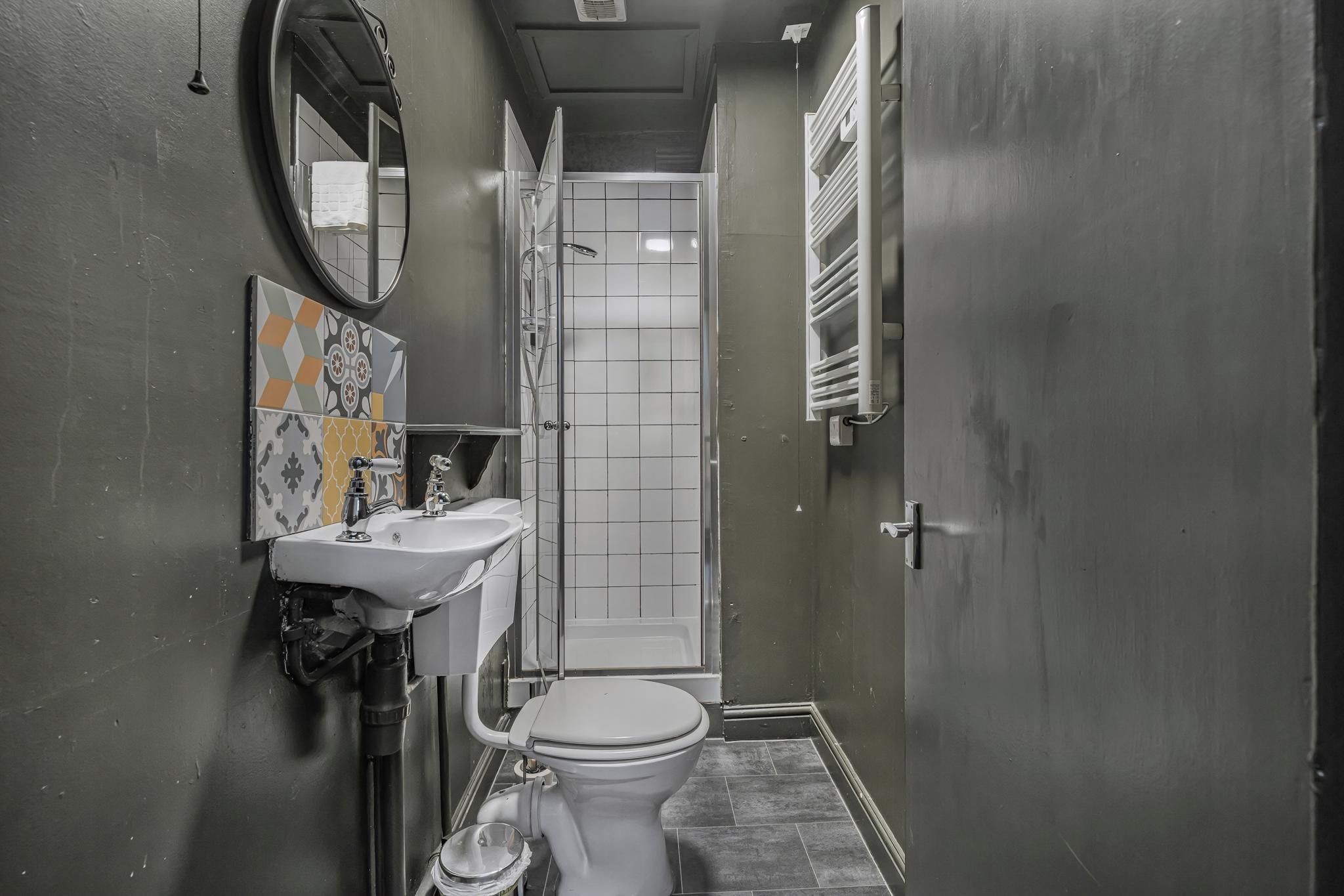 Ein schmales Badezimmer mit Waschbecken, Toilette und Dusche.