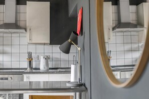 A kitchen with white cabinets, a black countertop, and a red object on the wall. - Guestready - Rose and Monkey (Manchester)
