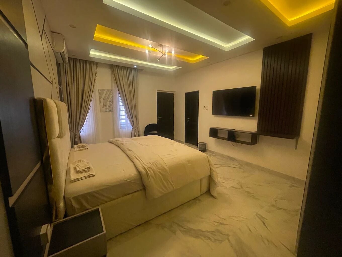 Una habitación de hotel moderna con una cama, un televisor y una lámpara en el techo.