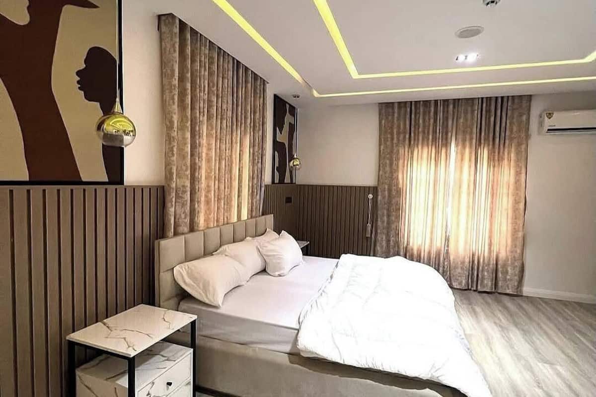 Un dormitorio moderno con cama, mesitas de noche y una pared decorada con un grabado silueteado.