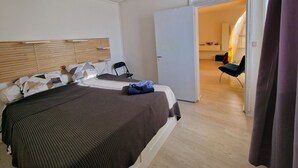 Une chambre à coucher comprenant un lit, une chaise, une armoire et une porte ouverte donnant sur une autre pièce.