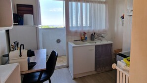 Une cuisine compacte avec un coin repas, une fenêtre avec des rideaux et une vue sur l’extérieur.