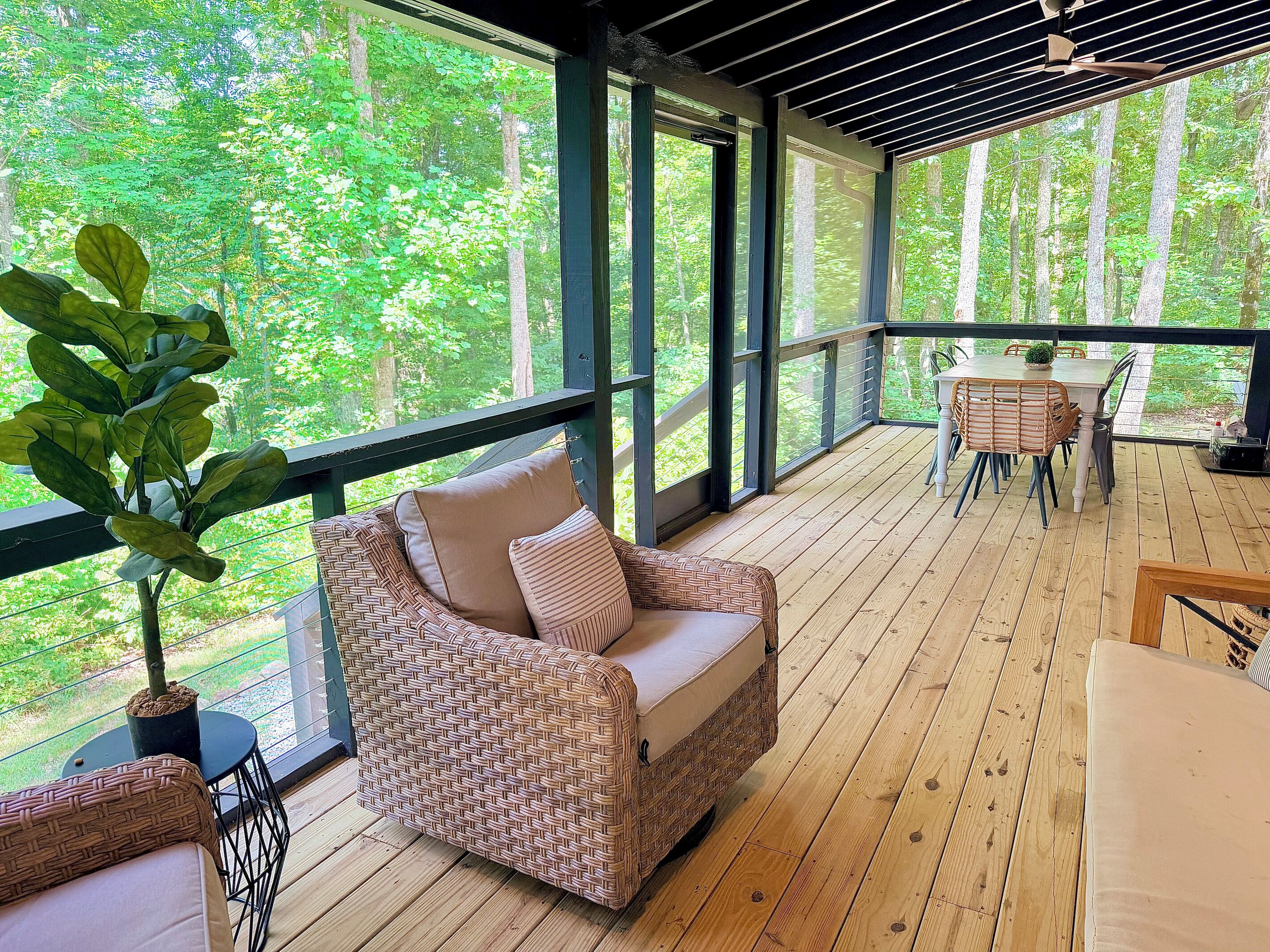 A covered outdoor seating area with wicker furniture, a table, and a potted plant.