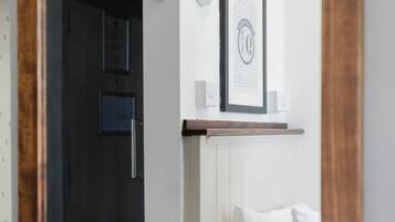 A hotel room with a bed, a framed certificate on the wall, a bedside lamp, and a door leading to a shower area.