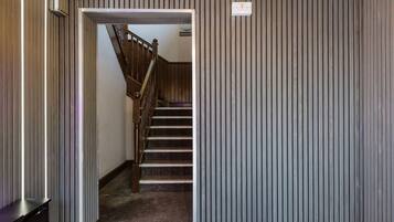 A hallway with a wooden staircase leading to a bedroom.
