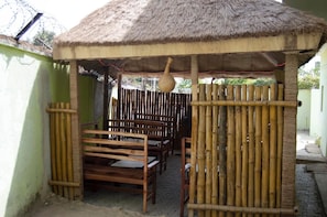 Una estructura con techo de paja, bancos de madera y cerca de bambú.
