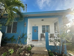 A blue building with a number 368 sign, a door with a 'welcome' sign, and a small porch area. - 3-bedroom cottage in Vieques w Wifi,  AC, breeze, free parking and pets friendly (Vieques)