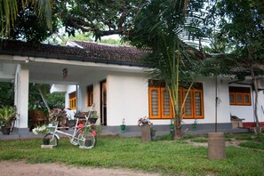 Een huis met een overdekte veranda, een fiets en potplanten.