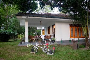 Een huis met een veranda, een fiets en planten in potten.